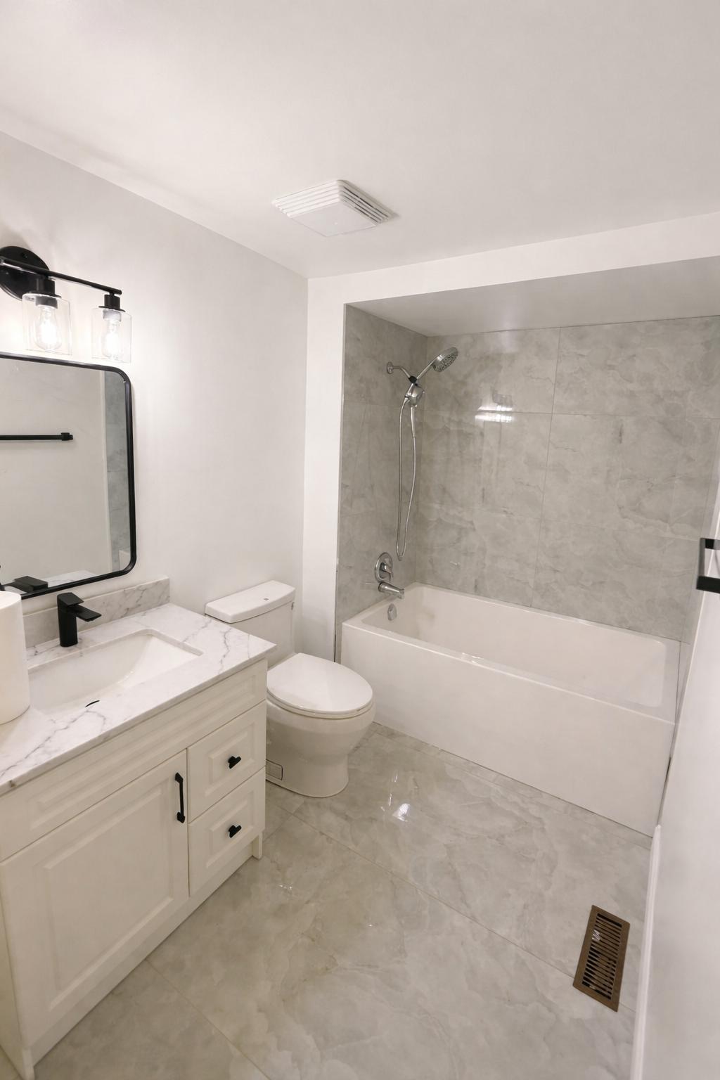 Clean white bathroom renovation with marble tile, black fixtures and tub shower combo by LevelUp Renos London Ontario