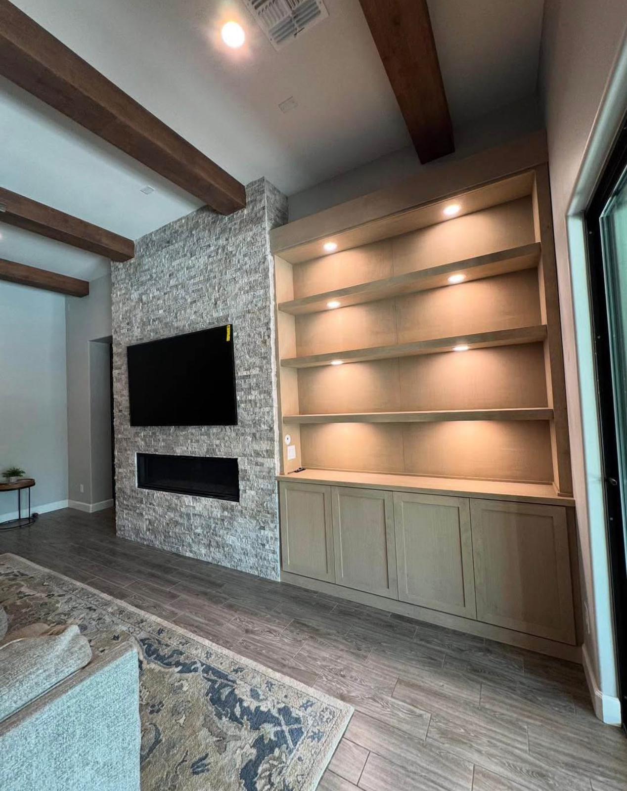Living room with stone fireplace wall and custom built-in shelving by LevelUp Renos