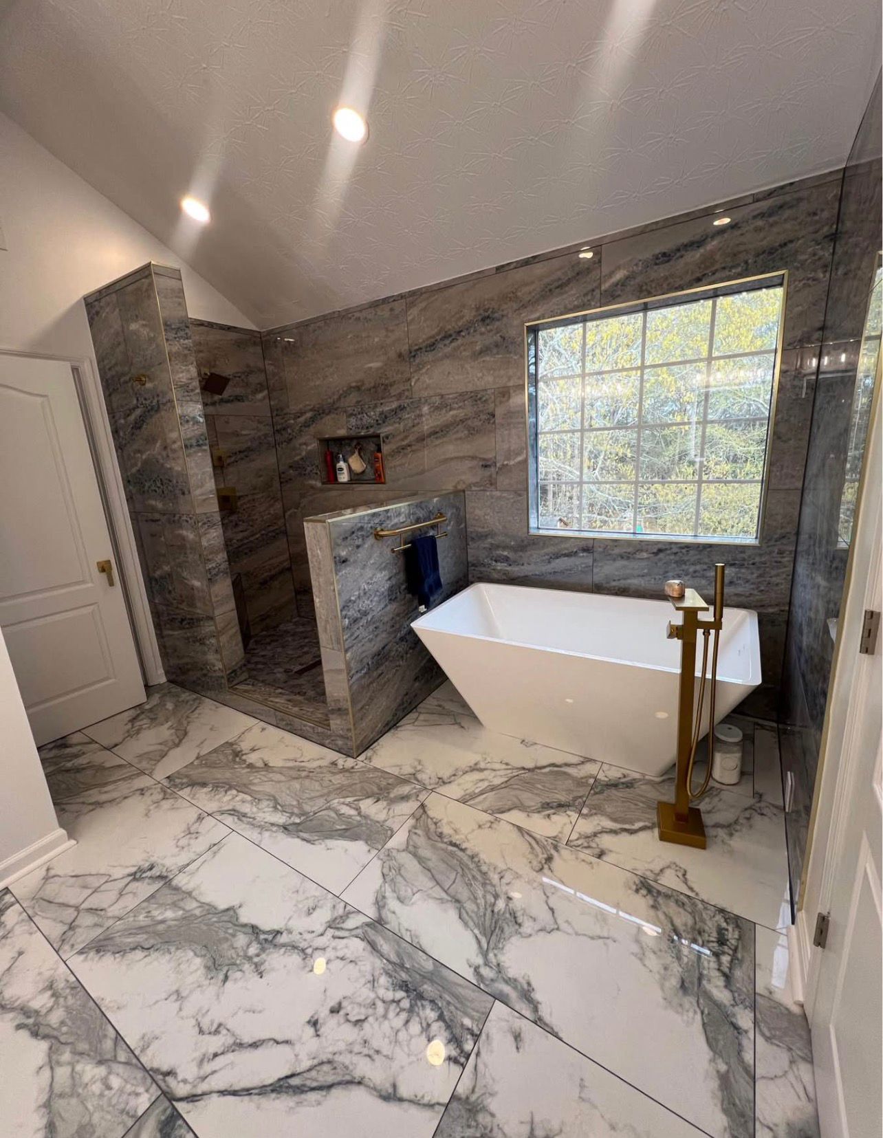 Luxury bathroom with marble floor tiles and gold fixtures by LevelUp Renos