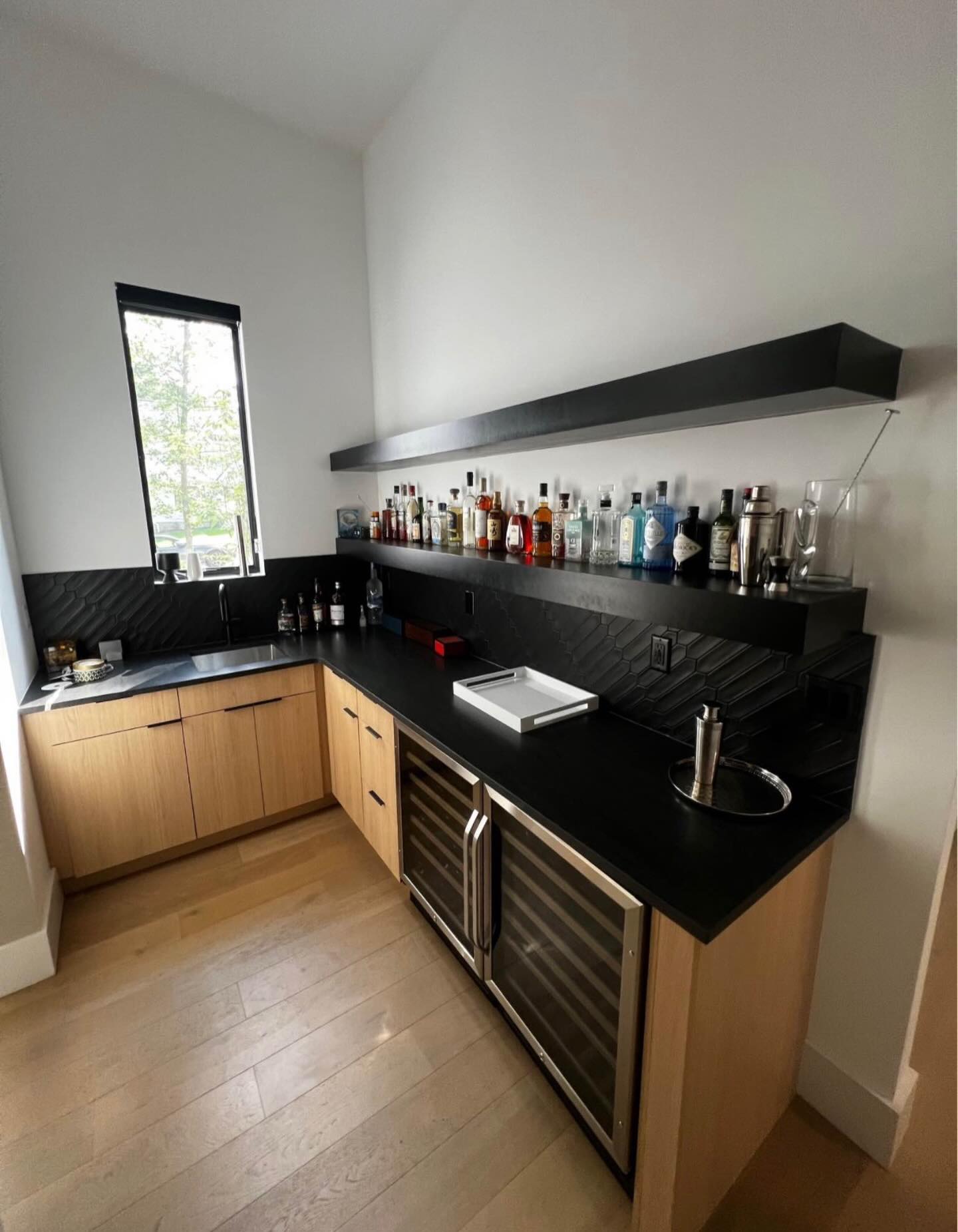 Custom wet bar with black countertops and wine fridge by LevelUp Renos