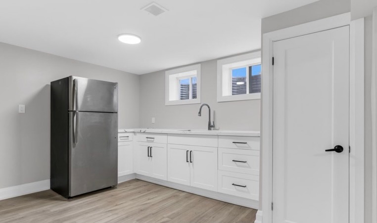 Basement apartment kitchen with white shaker cabinets, quartz countertops and stainless fridge by LevelUp Renos London Ontario