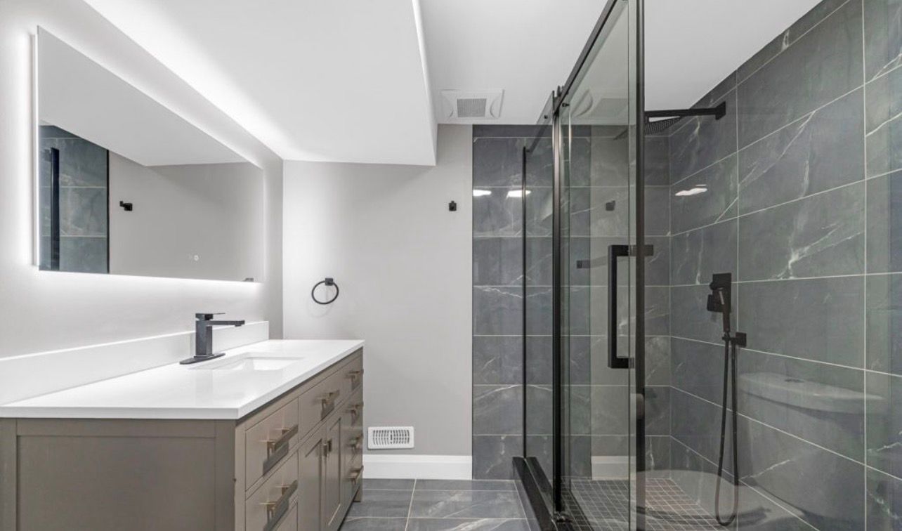 Modern bathroom with backlit mirror and marble tile shower by LevelUp Renos