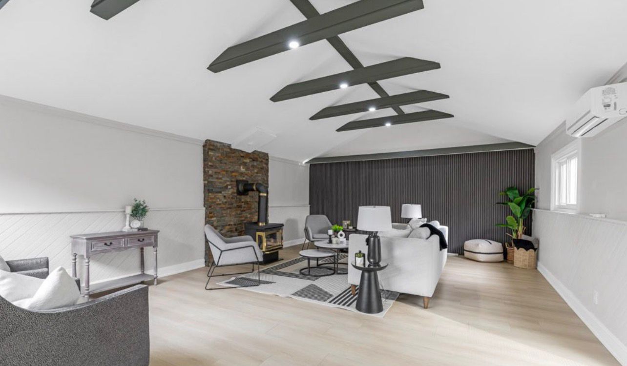 Vaulted ceiling living room renovation with exposed beams and fireplace by LevelUp Renos